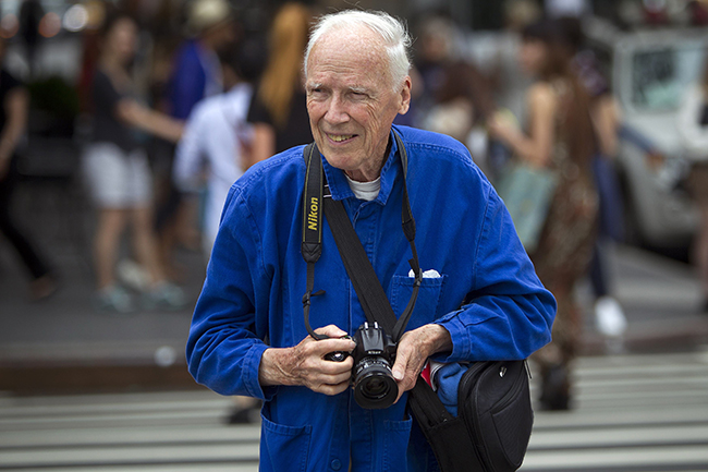 Bill Cunningham crosses the street after taking photos during New York Fashion Week in the Manhattan borough of New York